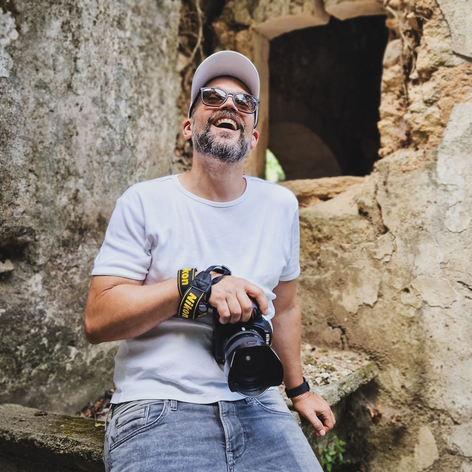 Een man in een wit overhemd houdt een Nikon-camera vast
