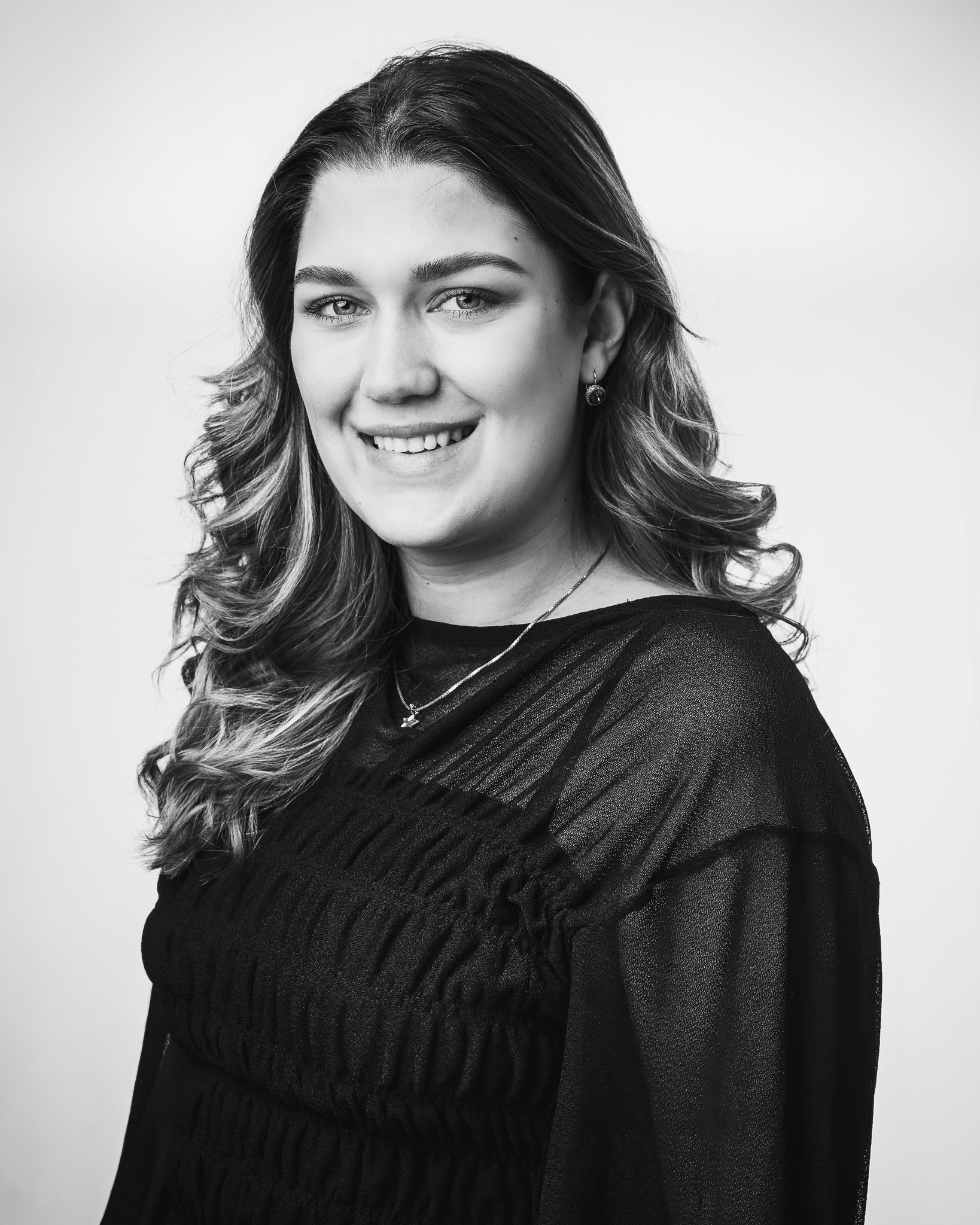 Een vrouw in een zwarte trui lacht op een zwart-witfoto