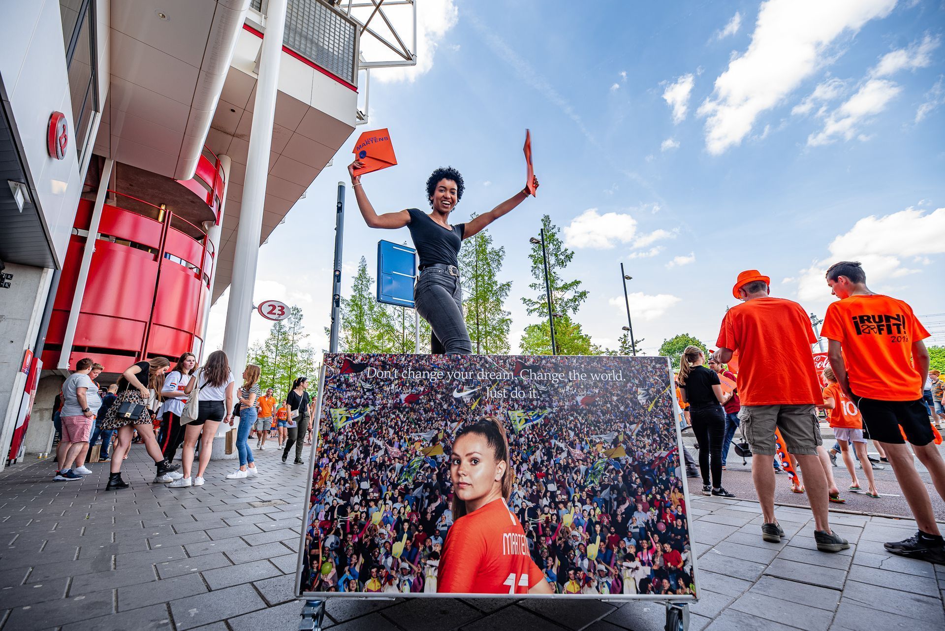 Een vrouw staat bovenop een groot schilderij van een vrouw.