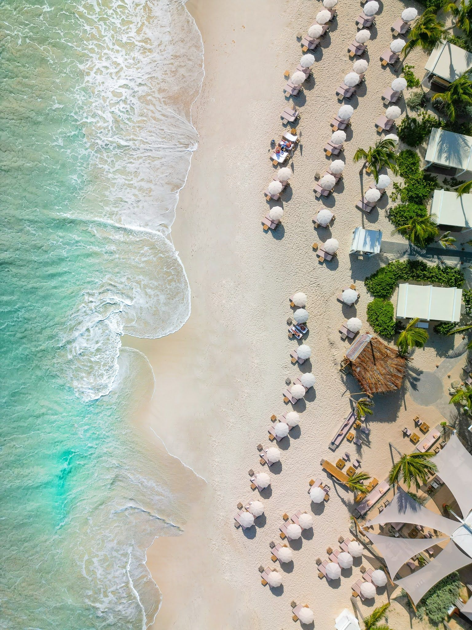 An aerial view of a beach with umbrellas and chairs.