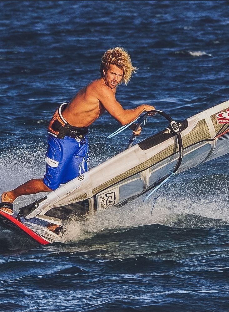 A man in blue shorts is riding a surfboard in the ocean