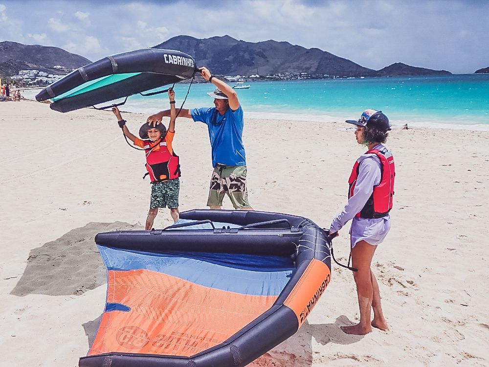 A man is teaching a child how to fly a kite on the beach.