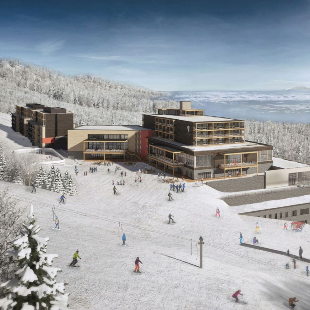 Bâtiments d'une station de ski sur une pente enneigée, avec des skieurs, dans un cadre montagneux.