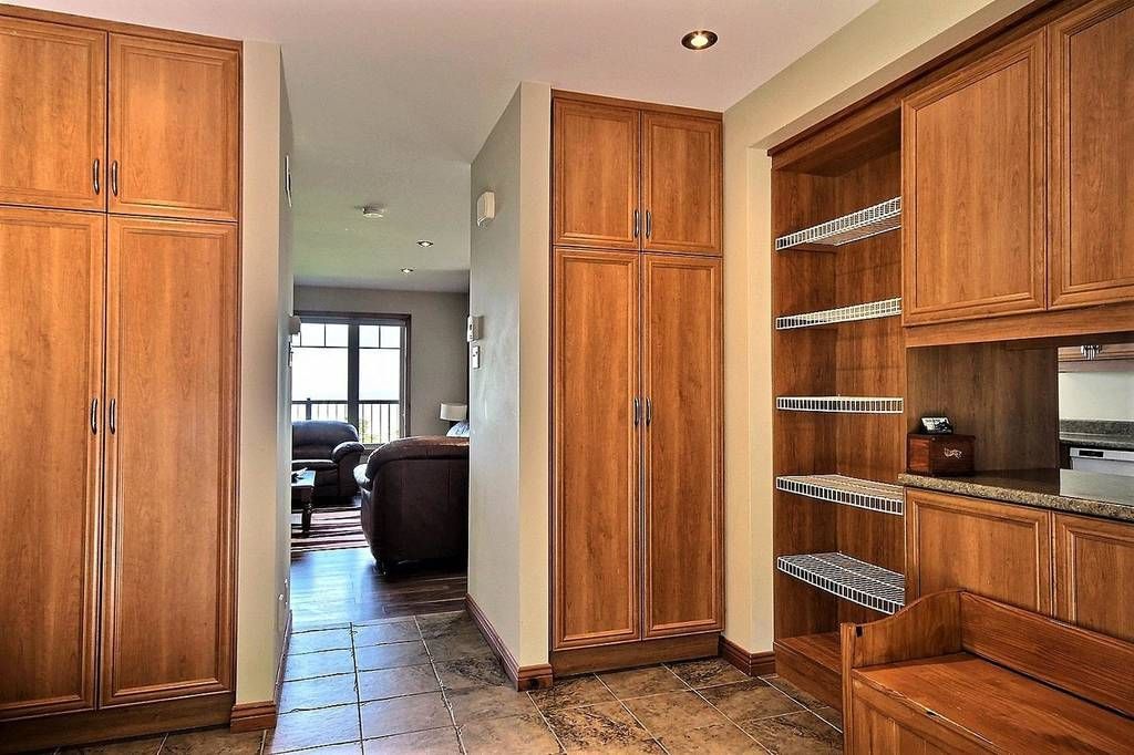 Wooden cabinets line a hallway with a tile floor, leading to a living room.