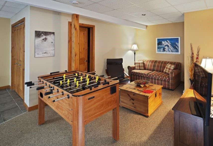 Baby-foot dans un salon, avec un canapé, une table basse et des éléments en bois.