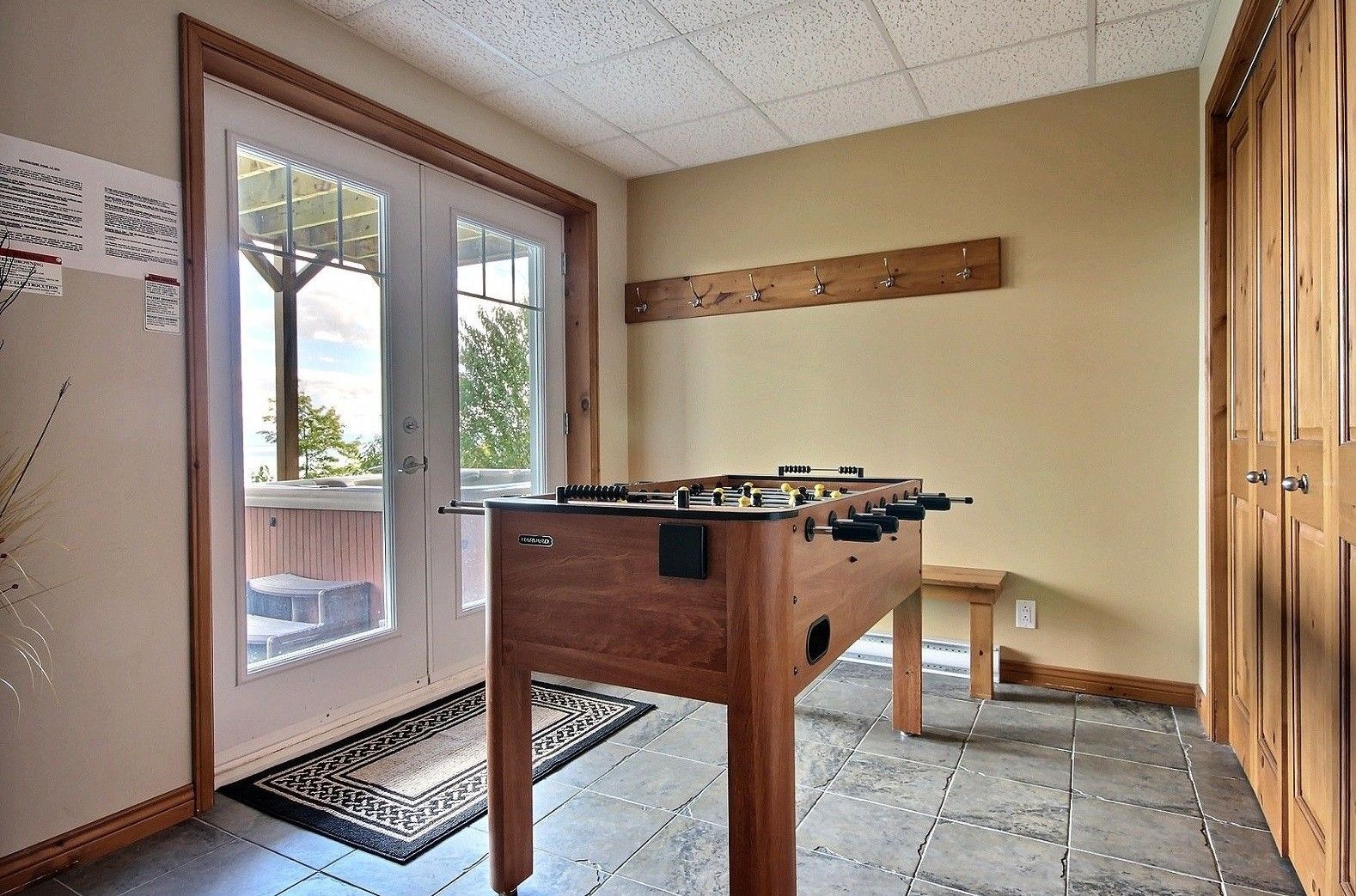 Table de baby-foot dans une pièce avec une porte, des murs beiges et des boiseries.