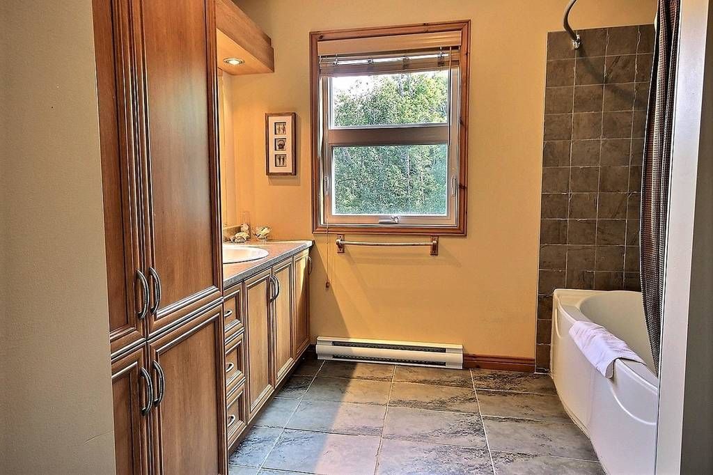 Salle de bains avec meuble-lavabo en bois, fenêtre et baignoire ; rénovation en cours.