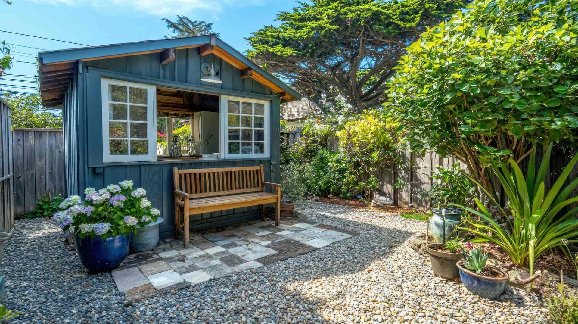 A small shed with a bench in front of it in a backyard.