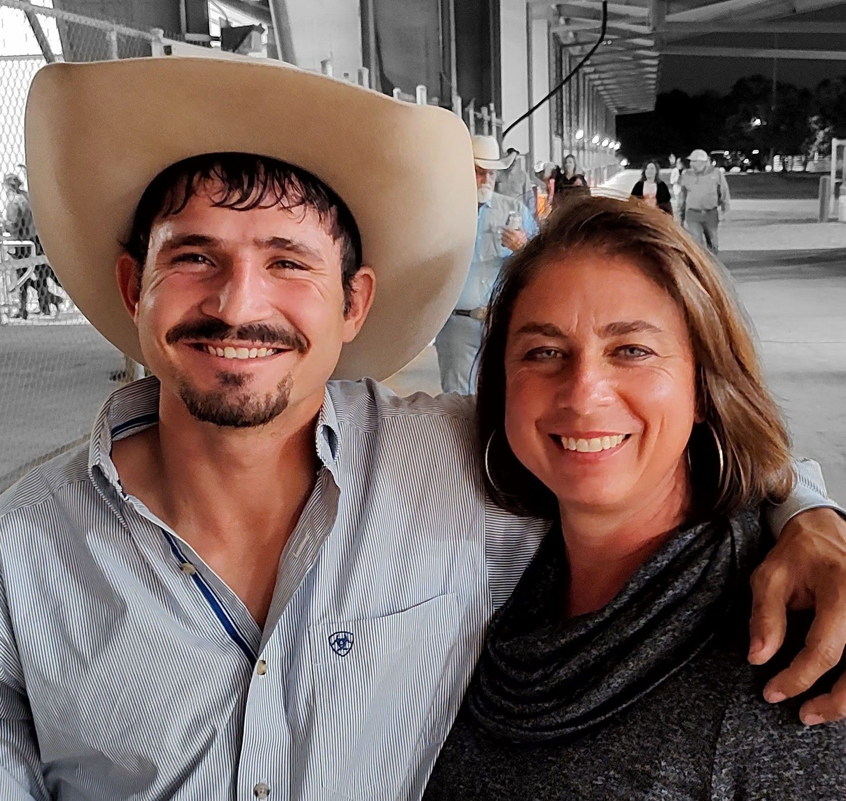 Man in cowboy hat and woman smile together outdoors.