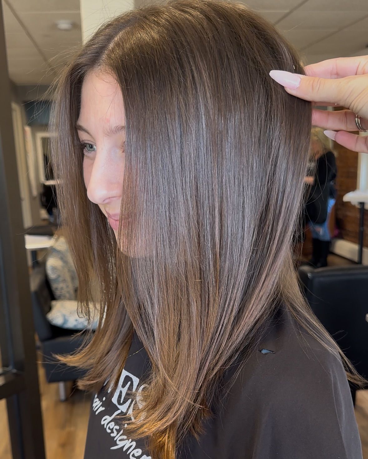 Hairdresser cutting dark hair with scissors and comb.