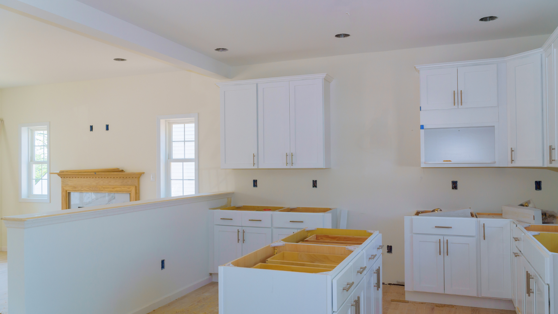 A kitchen under construction with white cabinets and a fireplace.