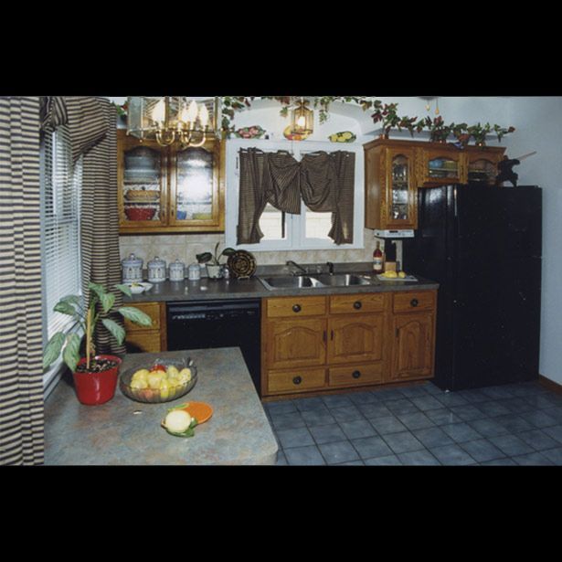 A kitchen with a black refrigerator and a bowl of fruit on the counter