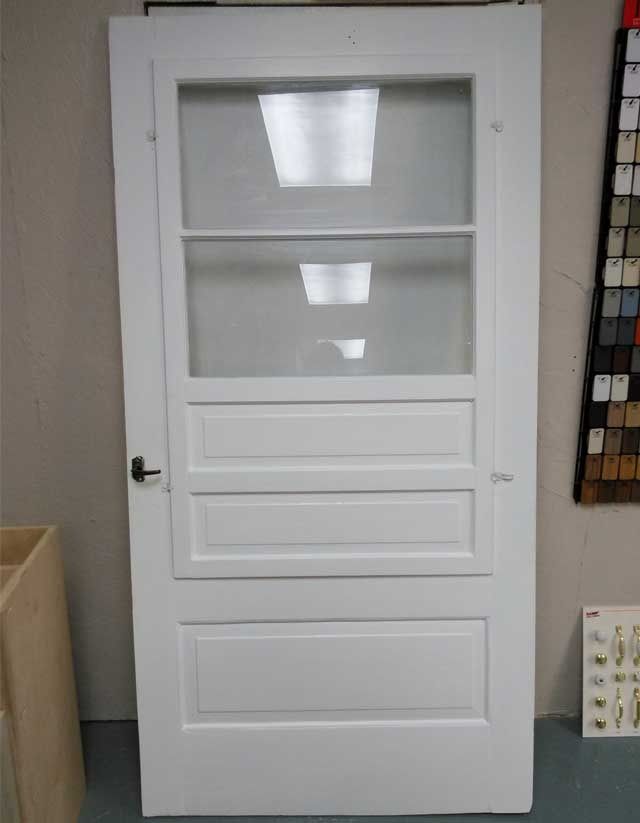 A white door with a glass window is sitting in a room.
