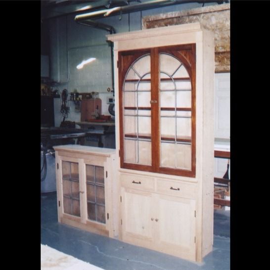 A wooden cabinet with glass doors and drawers
