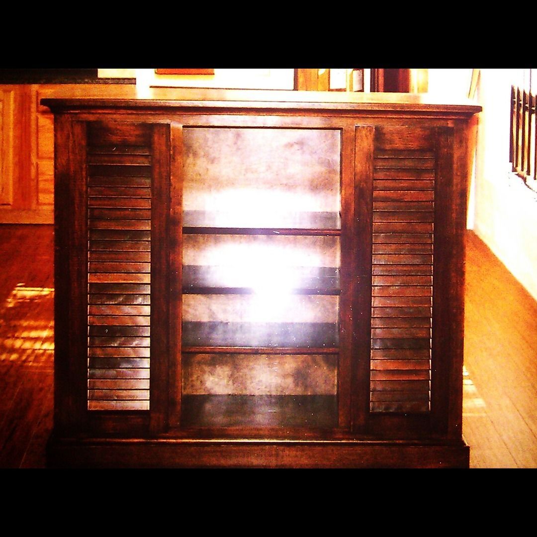 A wooden cabinet with shutters on the doors
