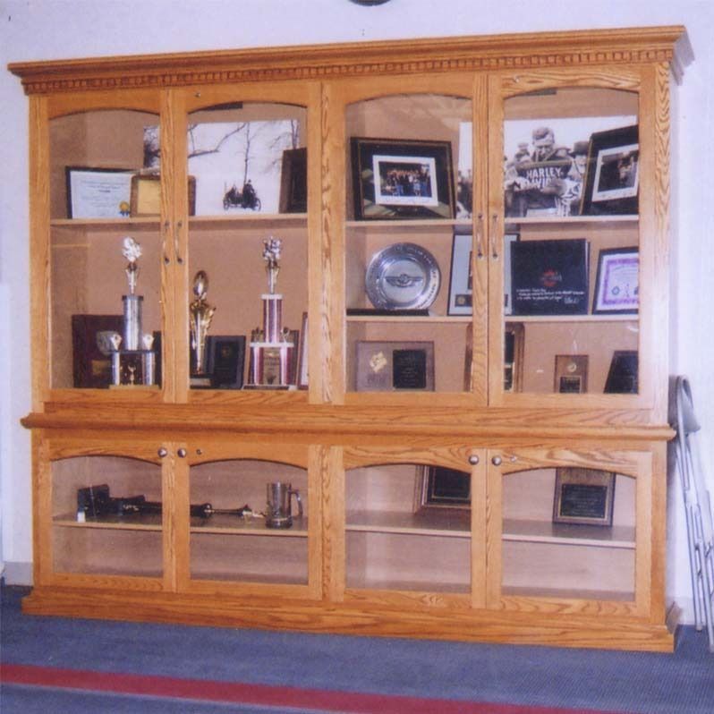 A large wooden cabinet filled with trophies and pictures