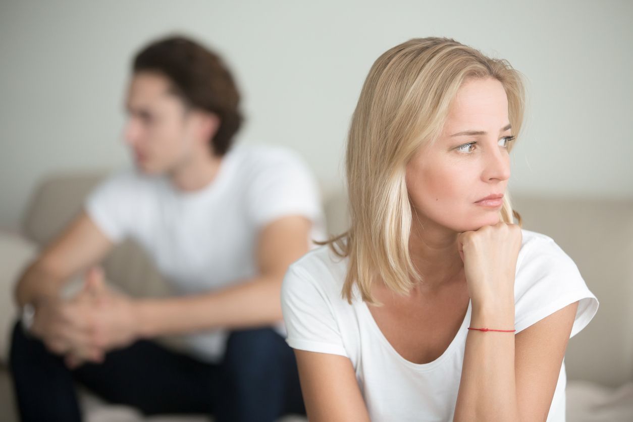 A man and a woman are sitting on a couch, looking away from each other