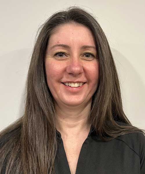 A woman with long brown hair is smiling and wearing a black shirt.
