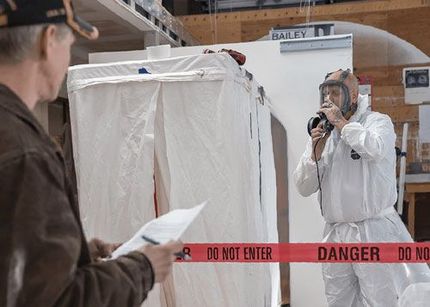 two men in protective suits are working on a building