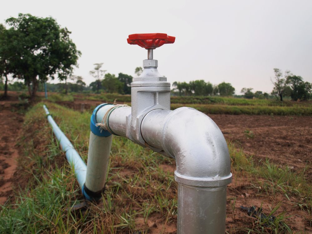 A close up of a water pipe with a red valve in a field — Proton Engineering Pty Ltd In Gunnedah, NSW