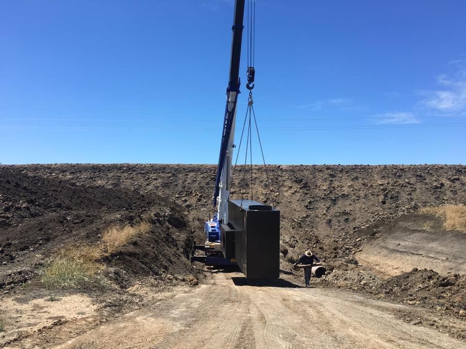 A Crane is Lifting a Large Box on a Dirt Road — Proton Engineering Pty Ltd In Moree, NSW