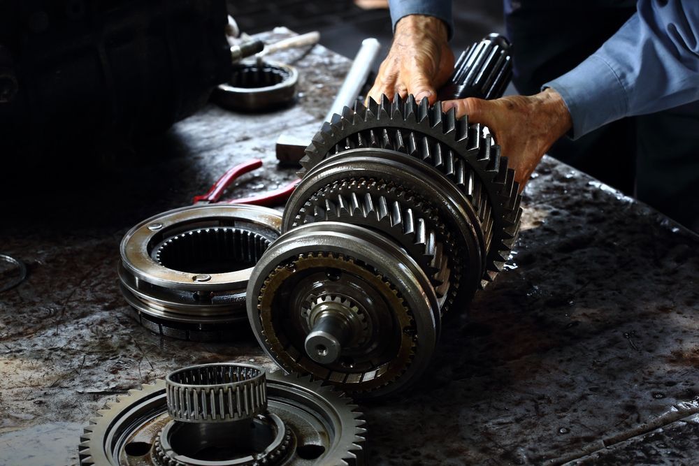 A Man Wearing Blue Shirt is Holding Gears — Proton Engineering Pty Ltd In Wee Waa, NSW