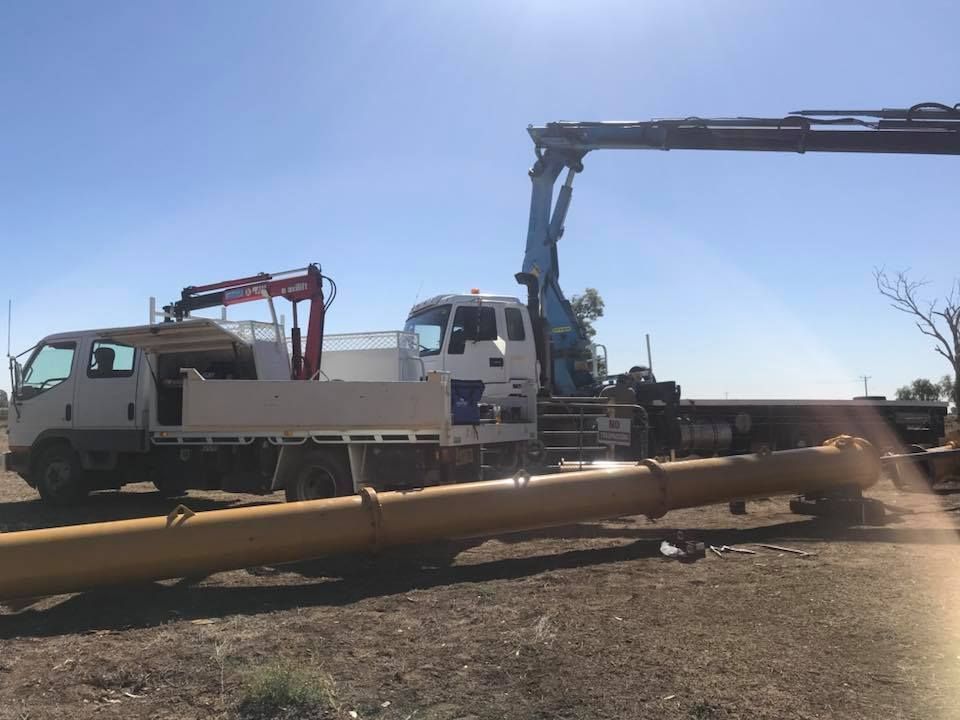 A Truck With a Crane Attached to It is Carrying a Large Pipe — Proton Engineering Pty Ltd In Wee Waa, NSW