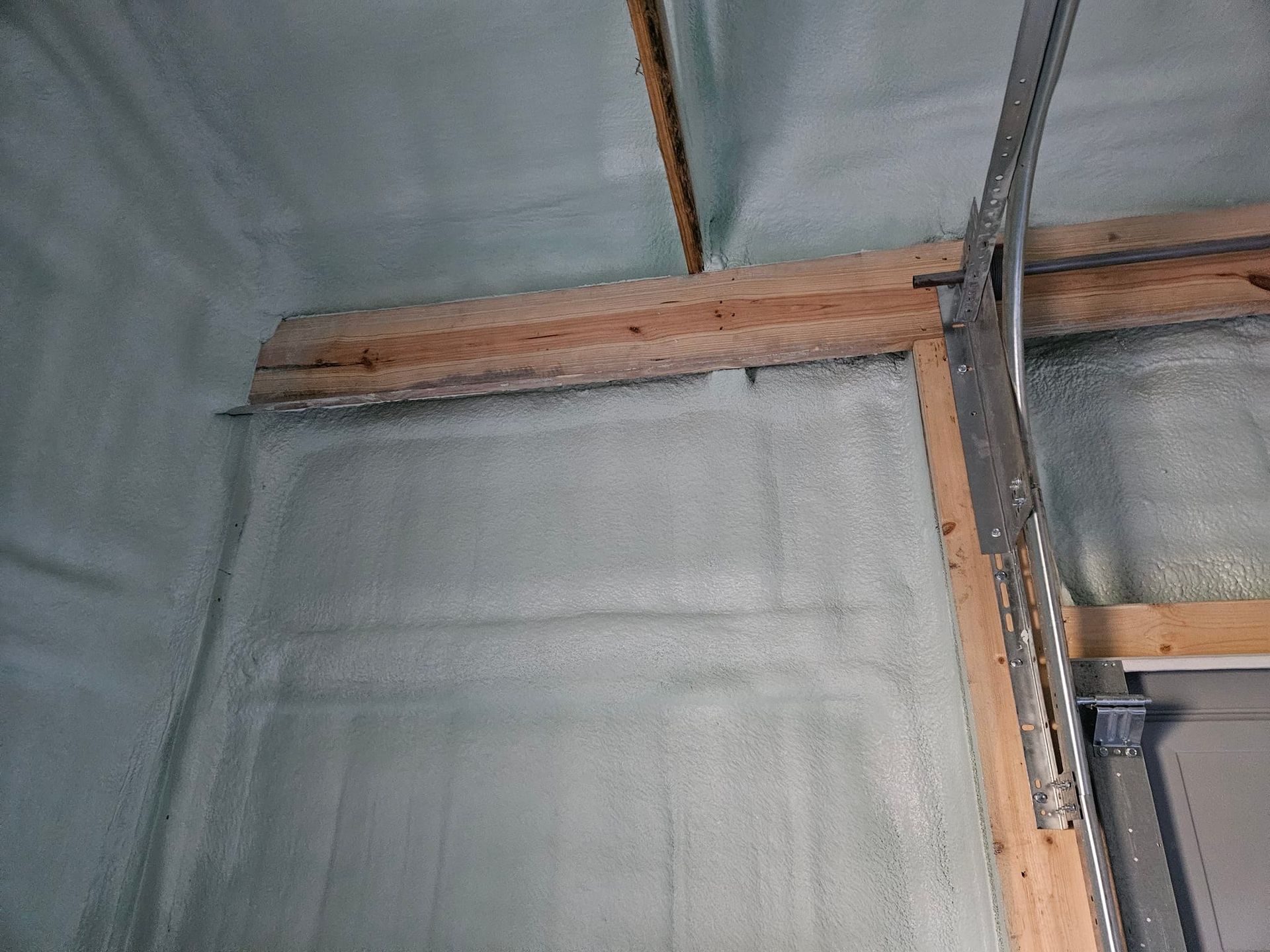 Interior wall with spray foam insulation covering the framing, including a wooden header.