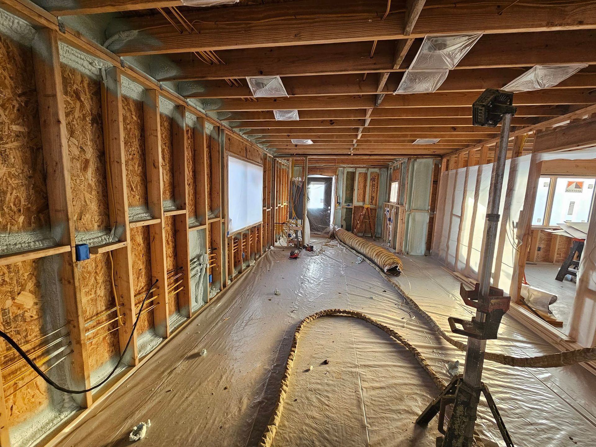 Interior of a building under construction. Wooden framing and insulation are visible. A light and doorway can be seen.