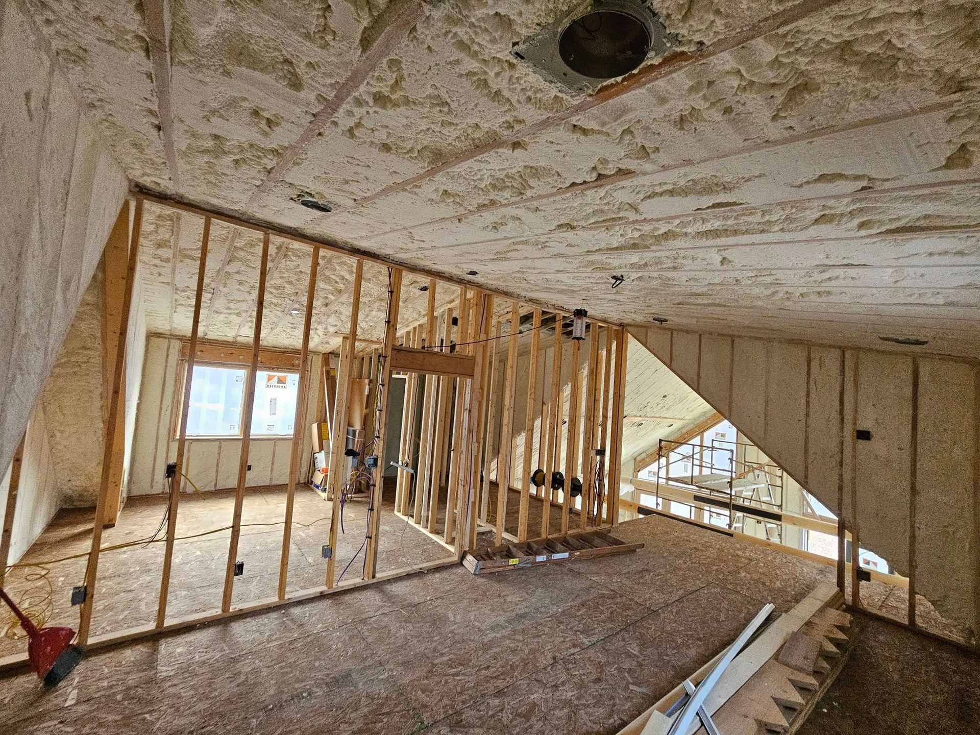 Interior view of a room under construction with exposed wooden framing and plywood walls.