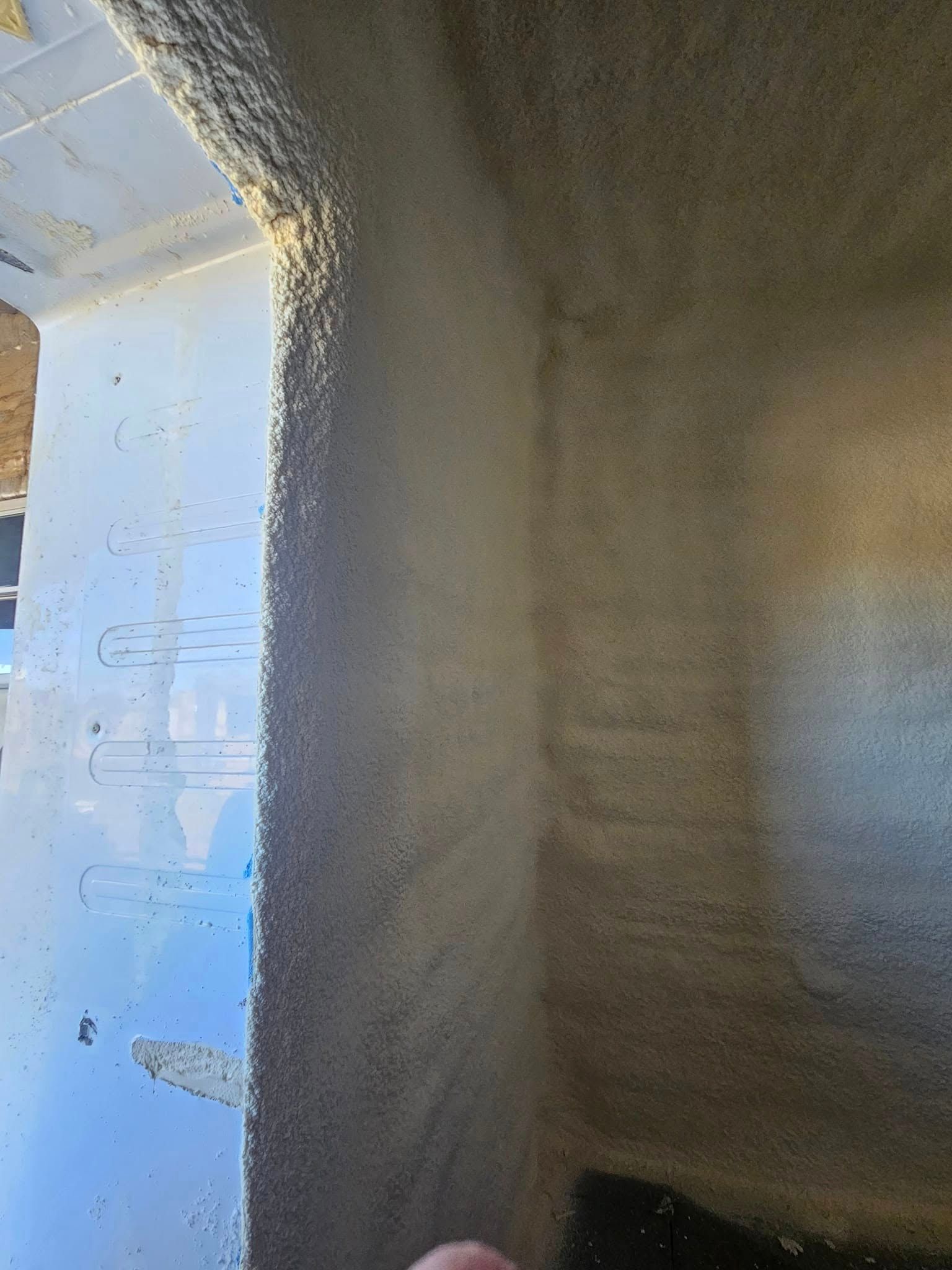 Corner of a room with light reflecting on the walls. The walls have a textured, granulated appearance.