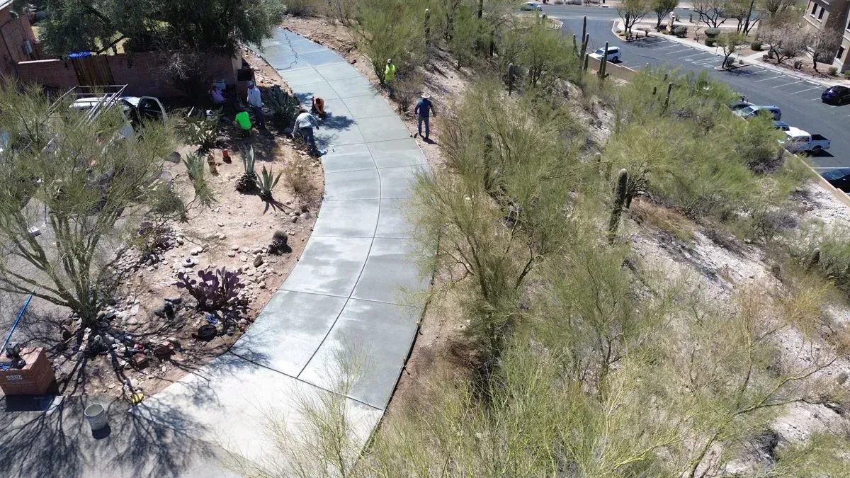 Concrete pathway winds through desert landscape with a person standing on it.