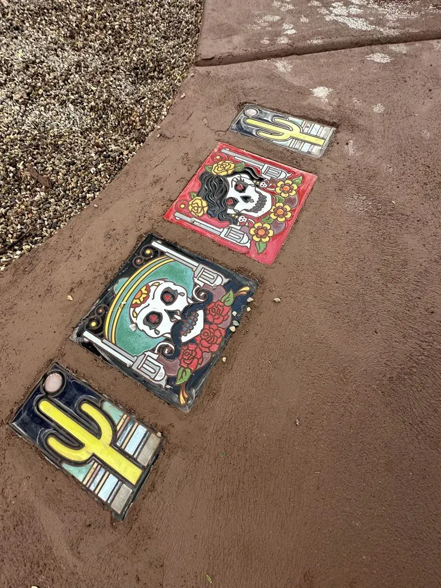 Pathway with decorative tiles featuring skulls and cacti designs.