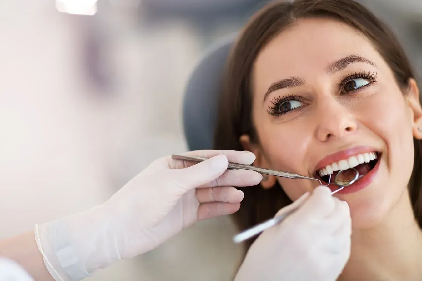 Woman at dentist, mouth open, smile. Dentist's gloved hands with tools examining teeth. Clinic setting. — McDonald Dental in Gympie, QLD