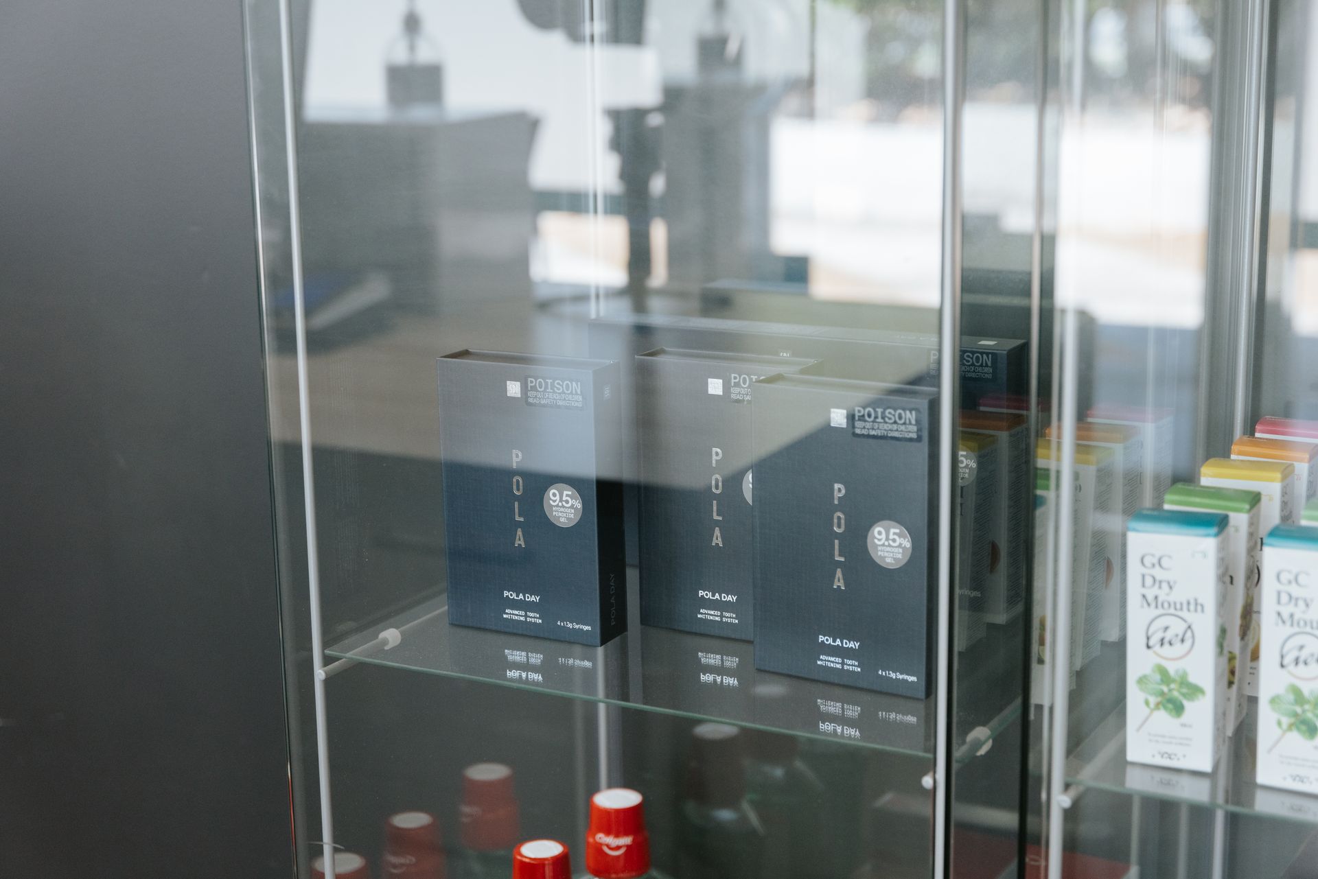 Boxes of products inside a clear display case. Shelves also hold bottles. — McDonald Dental in Gympie, QLD