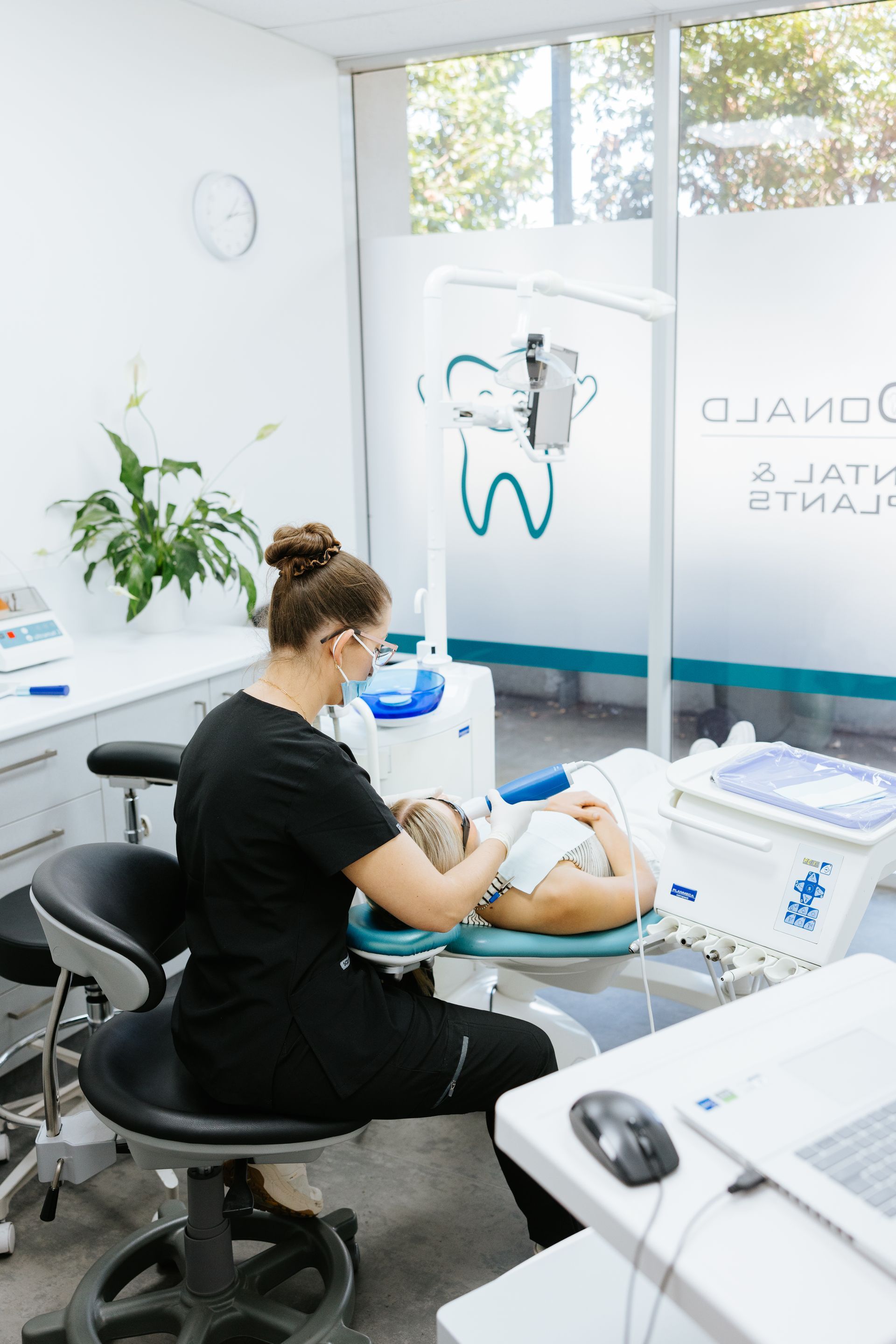 Dentist examining a patient's mouth in a bright dental office. — McDonald Dental in Gympie, QLD