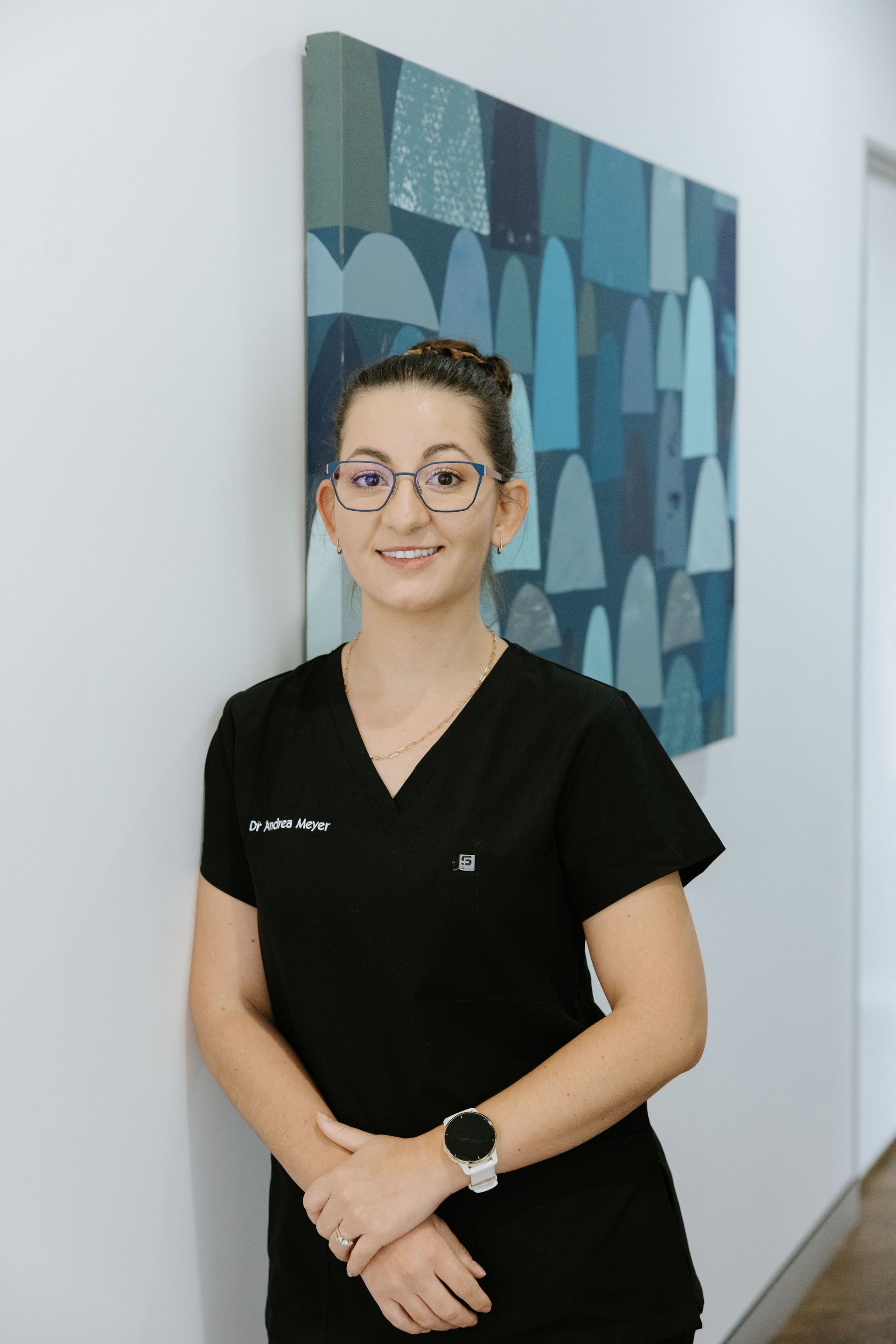 Woman in teal scrubs smiles, hands in pockets; white background. — McDonald Dental in Gympie, QLD