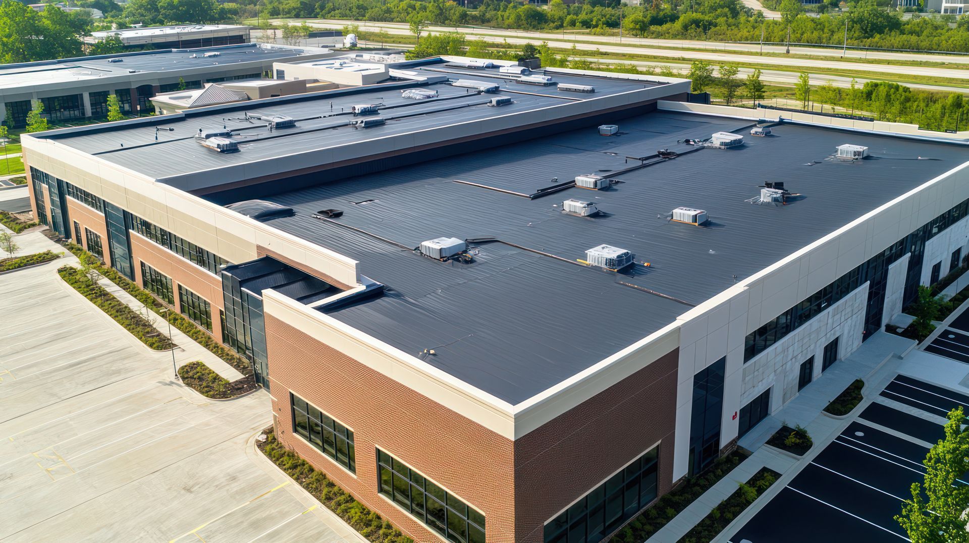 Aerial view of a large commercial building with a flat roof and parking lot.