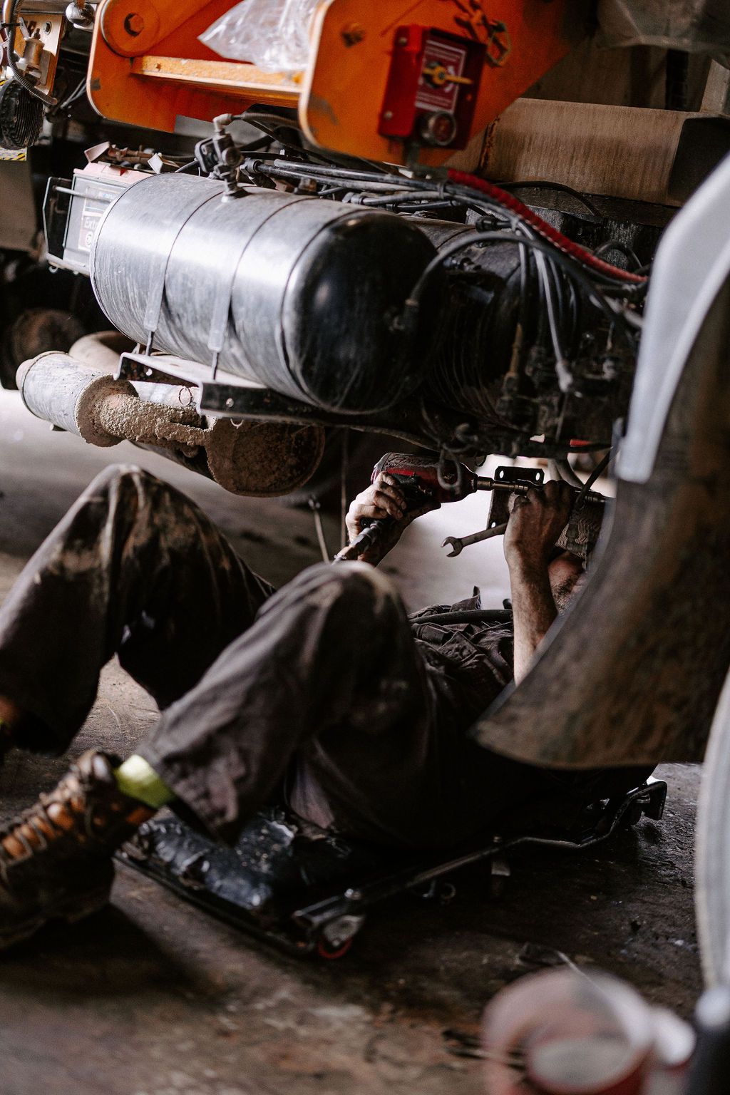 A Man Is Laying On The Ground Working On A Truck In A Garage — Tracserv in Dubbo, NSW