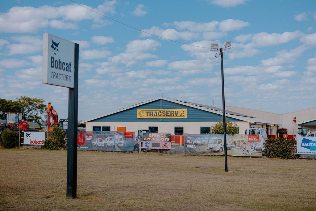 Bobcat Ranch sign, building, and grassy field against a blue sky with clouds.