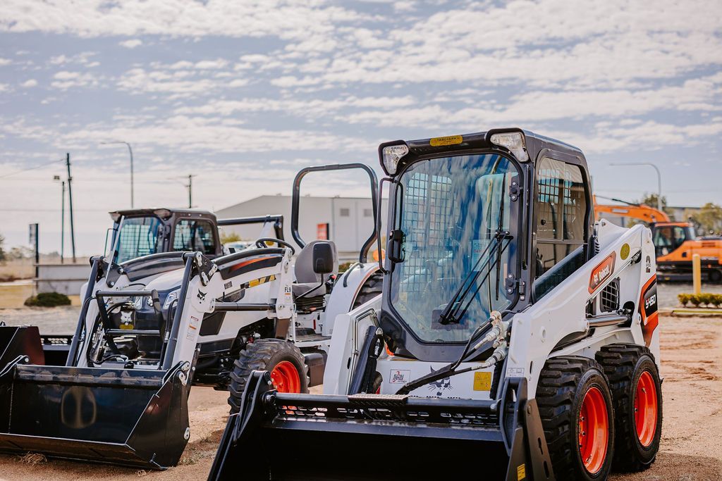 A Couple Of Tractors Are Parked Next To Each Other On A Dirt Road — Tracserv in Dubbo, NSW