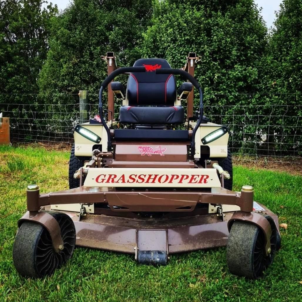 A Brown And White Grasshopper Lawn Mower Is Parked In The Grass — Tracserv in Orange, NSW