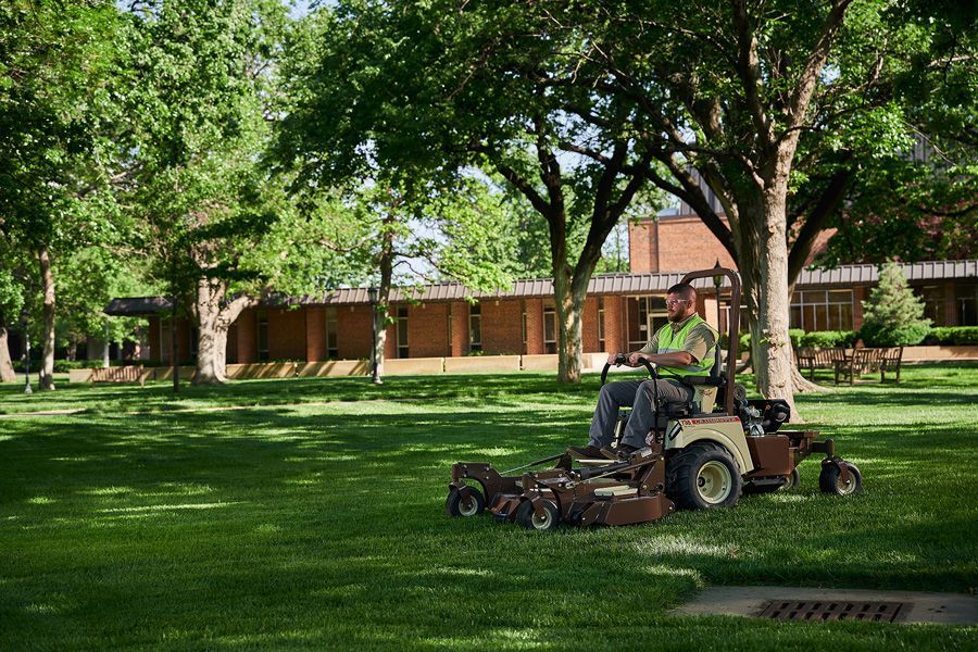A Man Is Riding A Lawn Mower On A Lush Green Lawn — Tracserv in Bourke, NSW
