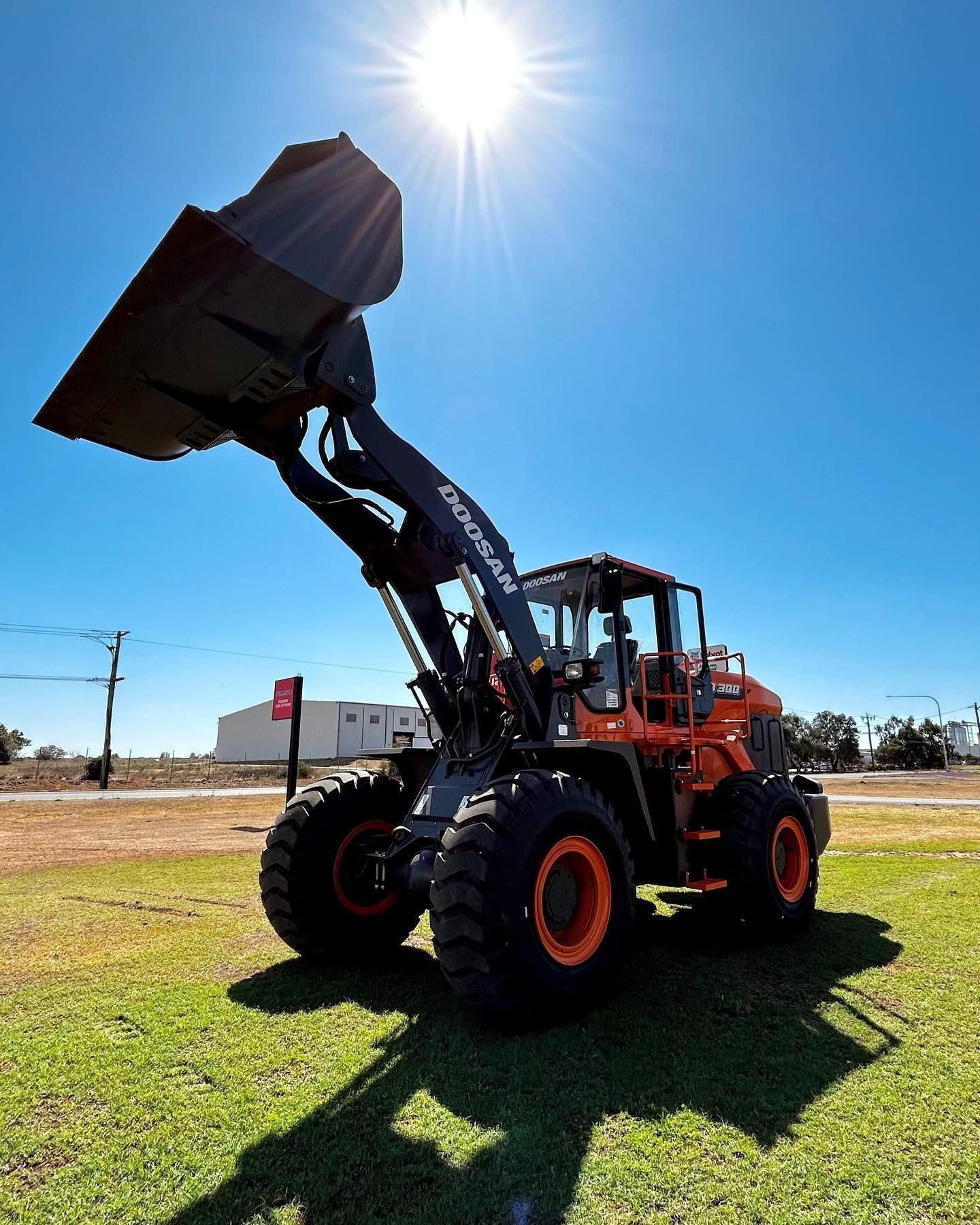 A Bulldozer With A Large Bucket Is Parked In A Grassy Field — Tracserv in Forbes, NSW