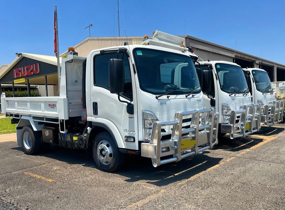 A Row Of White Dump Trucks Are Parked In A Parking Lot — Tracserv in Parkes, NSW