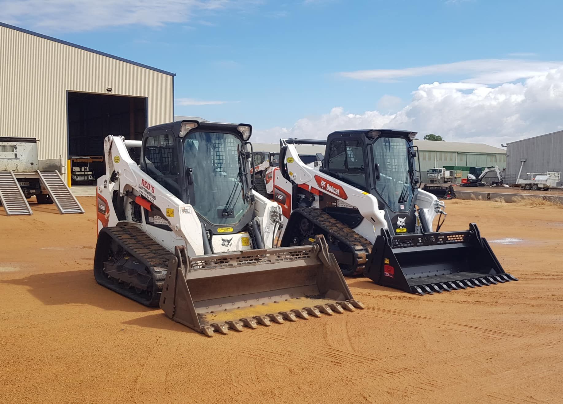Two Bulldozers Are Parked In A Dirt Lot In Front Of A Building — Tracserv in Mudgee, NSW