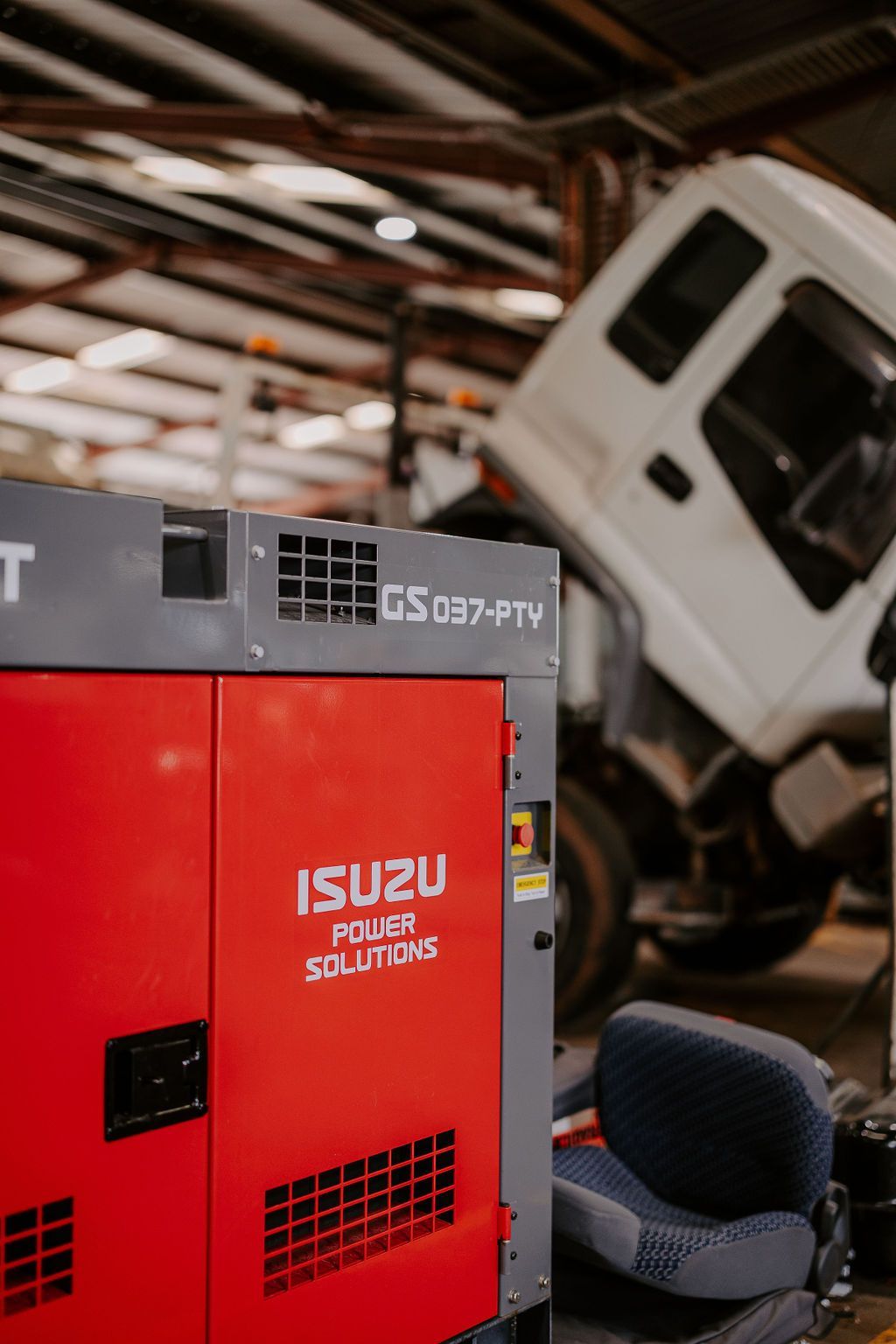A Red Isuzu Generator Is Sitting In A Garage Next To A White Truck — Tracserv in Dubbo, NSW