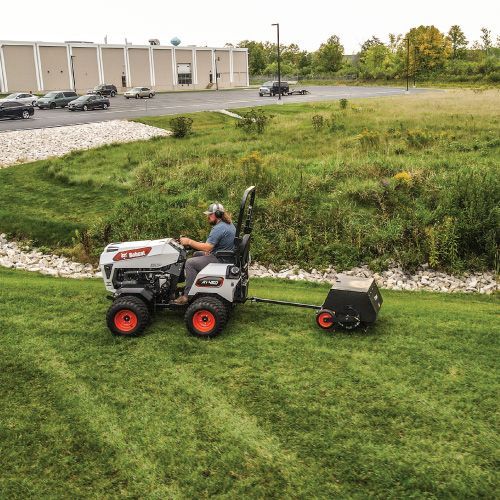 Man Operating a Bobcat Tractor with A Towed Aerator on A Grassy Slope — Tracserv in Dubbo, NSW