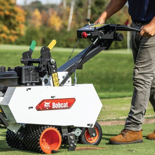 Man Operating a White Bobcat Aerator on A Green Lawn. Orange Wheels, Yellow/green Levers. Sunny Outdoors — Tracserv in Dubbo, NSW