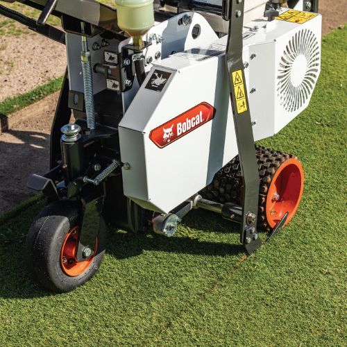 Bobcat Aerator on Green Grass, with Orange Wheels and A White Body — Tracserv in Dubbo, NSW